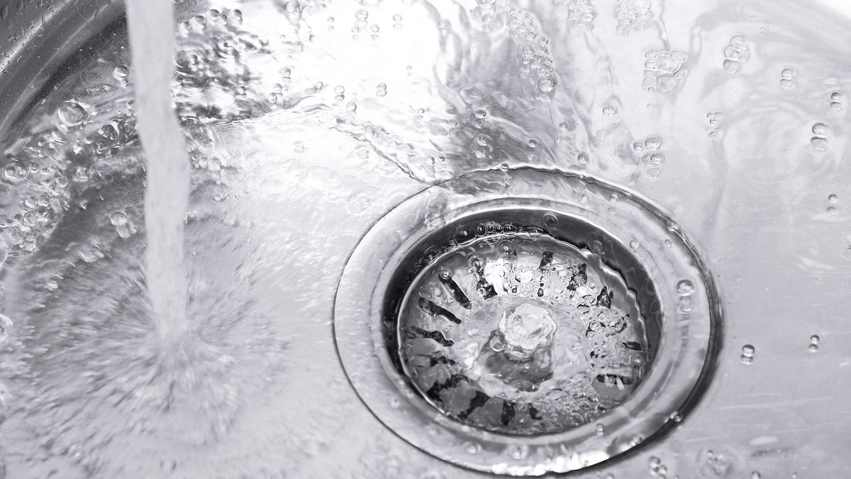 Water running freely down the strainer of a stainless steel kitchen sink