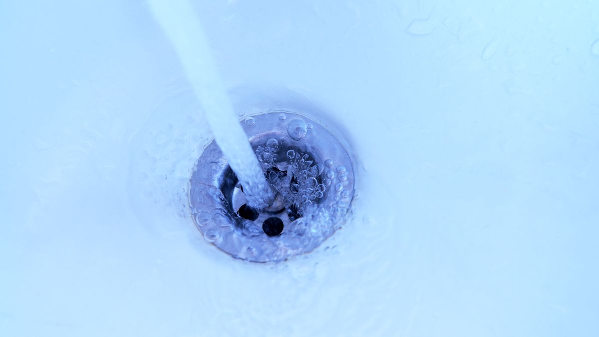 Close-up of a stainless steel sink drain with water running into it