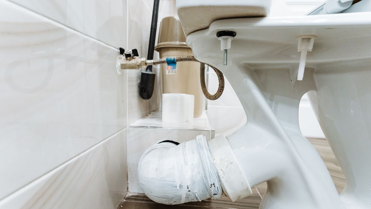 PVC drainage pipework exposed beneath a toilet during installation